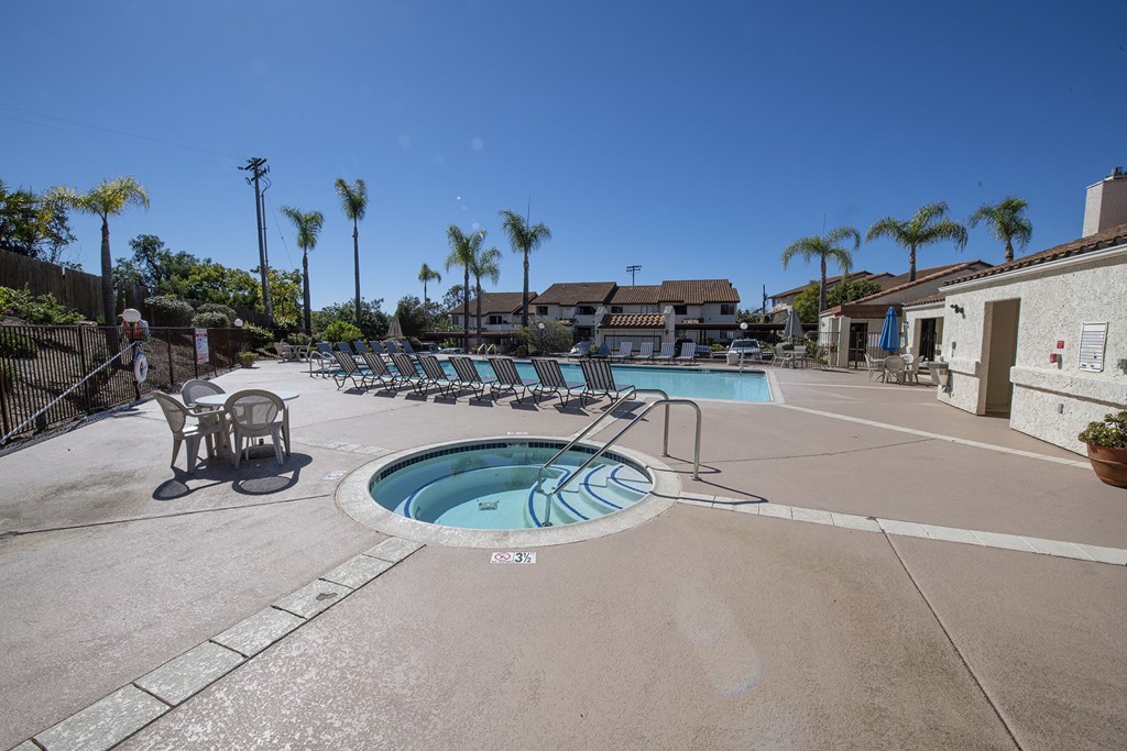 a swimming pool with chaise lounge chairs and a hot tub with palm trees at Sycamore Hills Village Apartments, Vista, California
