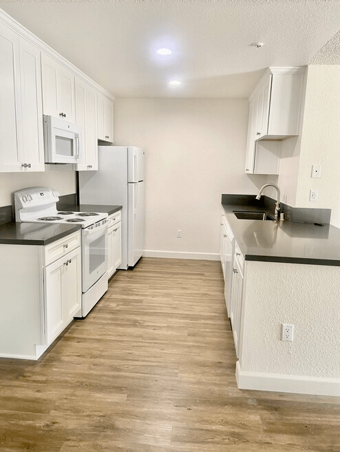 a kitchen with white cabinets and appliances and a wood floor at Sycamore Hills Village Apartments, California, 92081