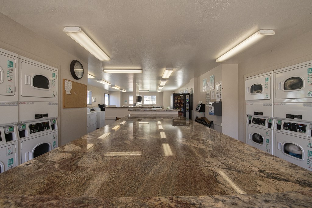a laundry room with washers and dryers and a granite counter top and a at Sycamore Hills Village Apartments, California