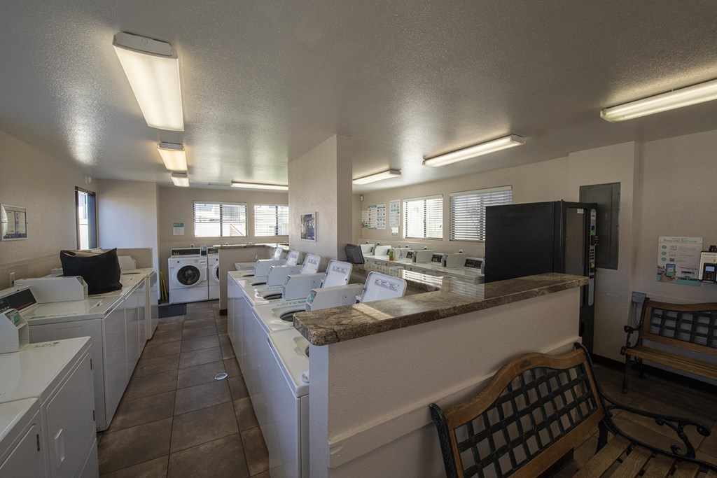a laundry room with washers and dryers and a table with a chair at Sycamore Hills Village Apartments, Vista, CA, 92081