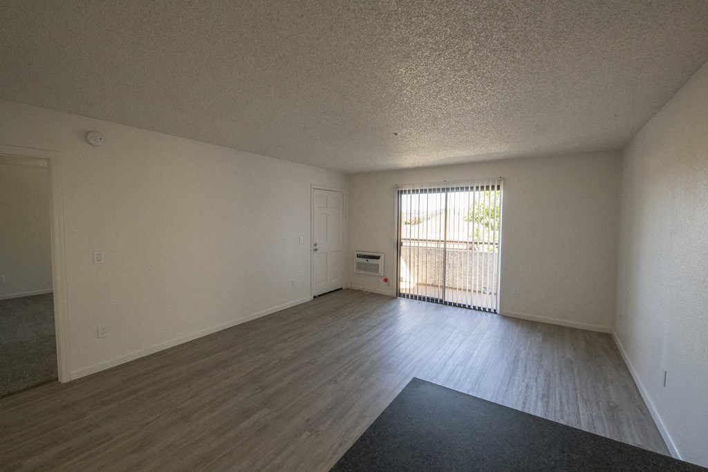 an empty living room with wood flooring and a window at Sycamore Hills Village Apartments, Vista, California