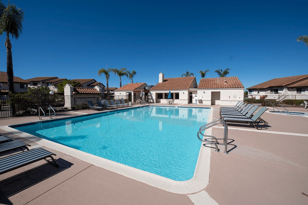 a swimming pool with chairs around it in front of a house at Sycamore Hills Village Apartments, Vista, CA, 92081