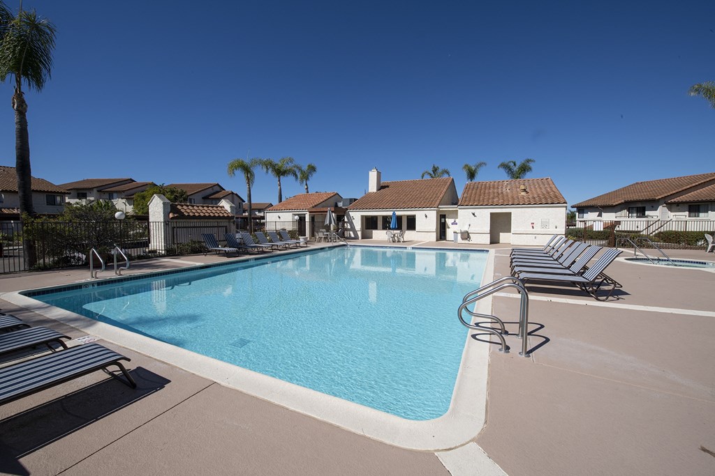 a swimming pool with lounge chairs around it in front of a house at Sycamore Hills Village Apartments, Vista, CA, 92081