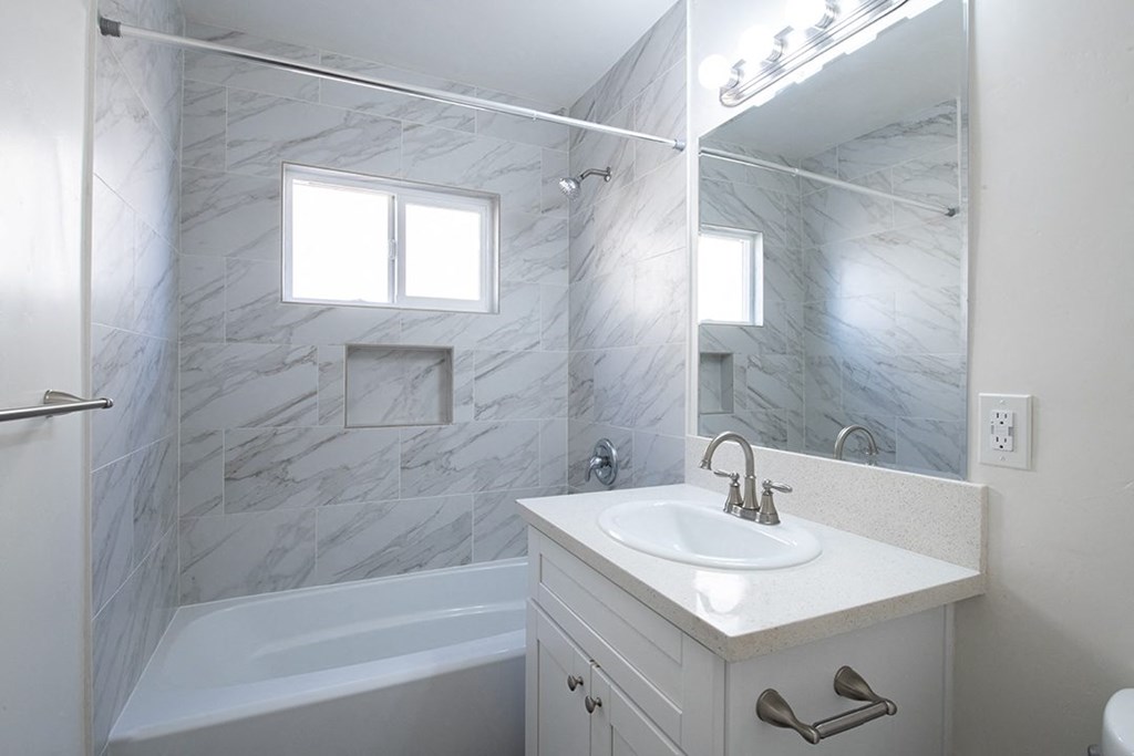 a bathroom with a sink and a tub and a mirror at Villa Primavera Apartments, California