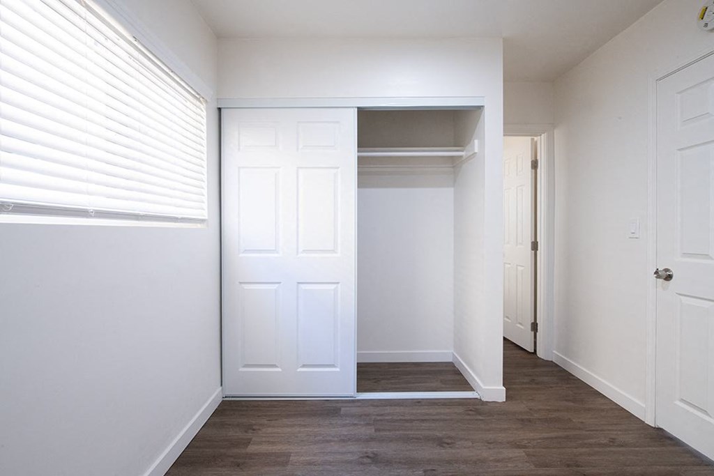 a bedroom with white walls and a closet with a white door at Villa Primavera Apartments, National City