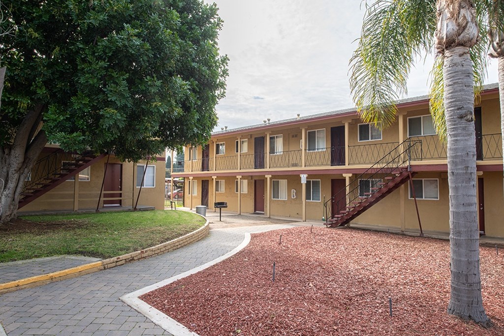 an exterior view of a yellow apartment building with a courtyard at Villa Primavera Apartments, National City