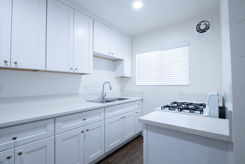 a kitchen with white cabinets and white counter tops and a sink at Villa Primavera Apartments, National City, 91950