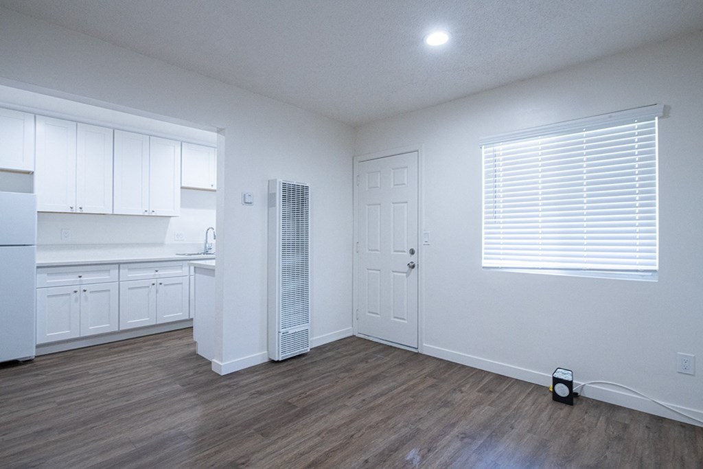 an empty kitchen with white cabinets and a refrigerator at Villa Primavera Apartments, California