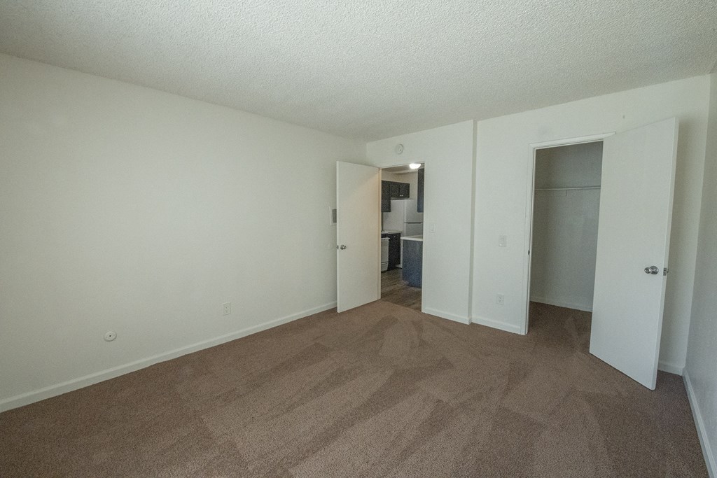 an empty living room with wood flooring and a closet at Villa Quixote Apartments, Escondido
