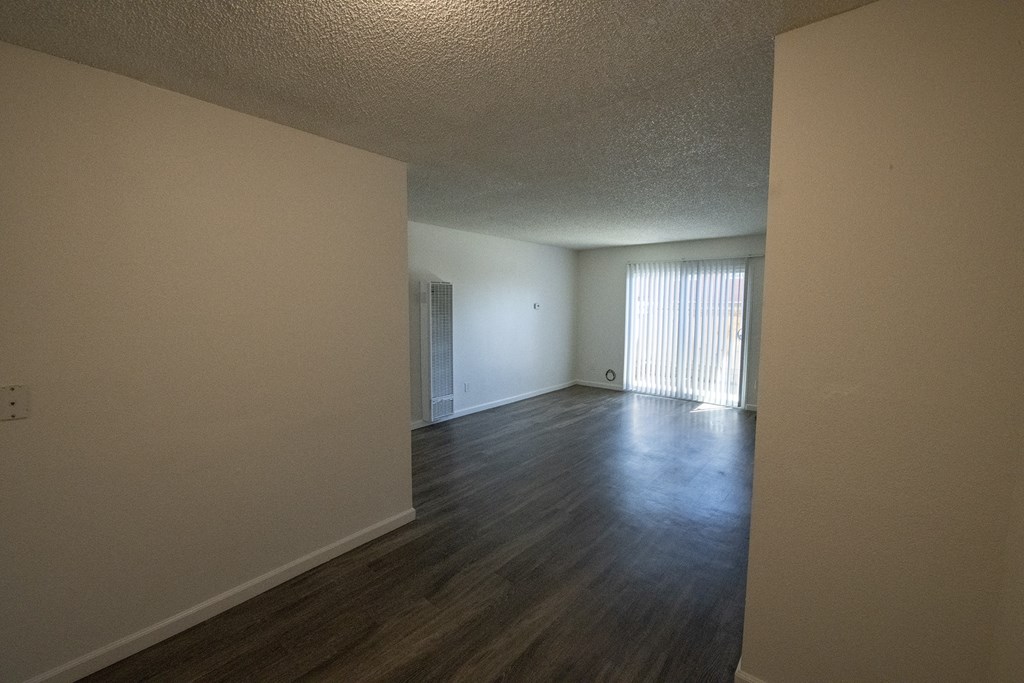 an empty living room and dining room with wood flooring  at Villa Quixote Apartments, California