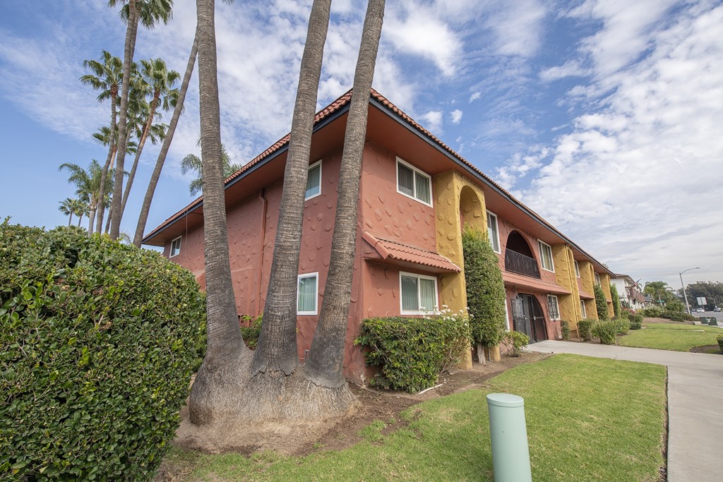 a pink house with three palm trees in front of it at Villa Quixote Apartments, Escondido
