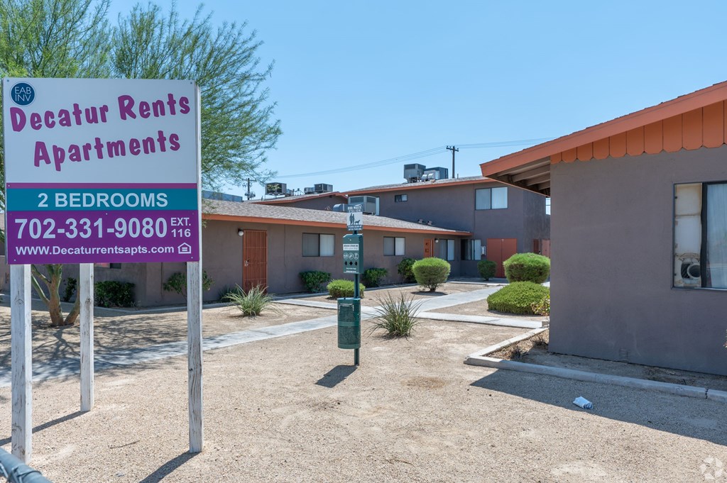 A sign for Decatur Rents Apartments with a phone number and website listed.