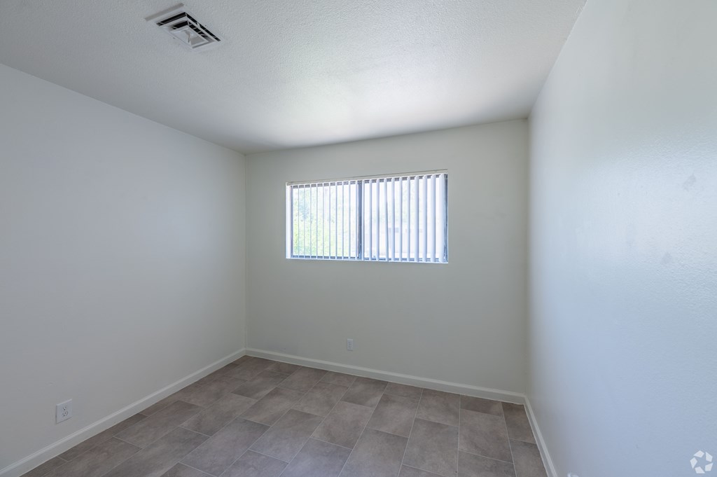 A bedroom with a window covered by blinds.