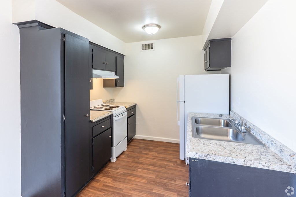 A kitchen with a white fridge and a marble countertop.