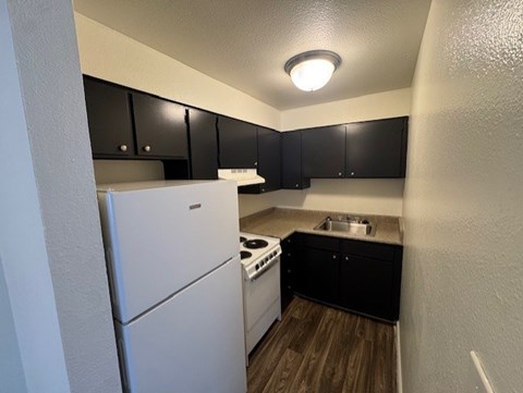 A small kitchen with black cabinets and a white refrigerator.