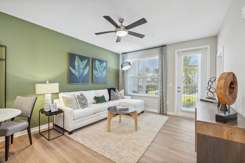 a living room with green walls and a ceiling fan