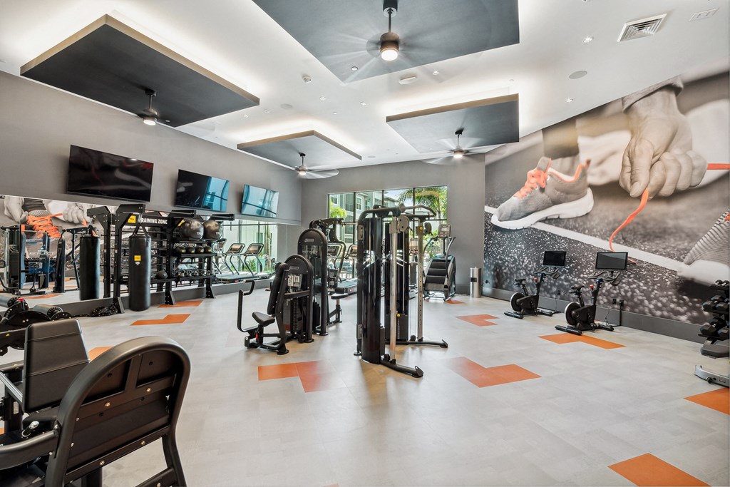 a large fitness room with cardio equipment and a large mural of a person on the wall