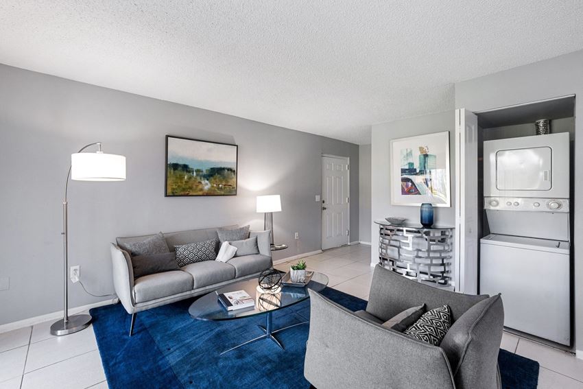a living room with couches and chairs and a blue rug