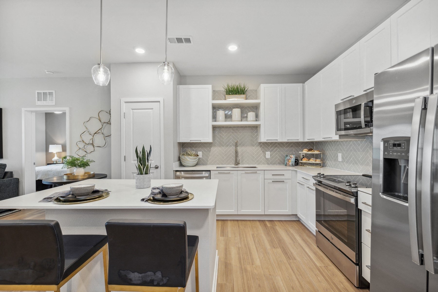 an open kitchen and dining area with white cabinets and stainless steel appliances