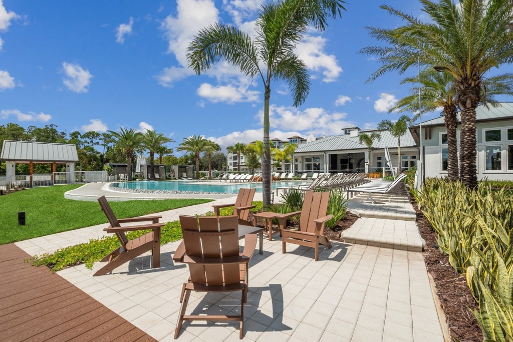a resort style pool with chairs and palm trees