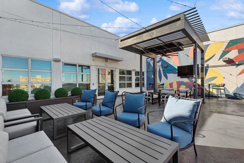 an outdoor patio with tables and chairs and a television