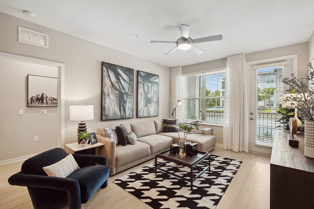 a living room with a ceiling fan and large windows