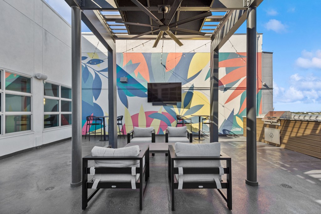 a patio with a table and chairs and a mural on the wall