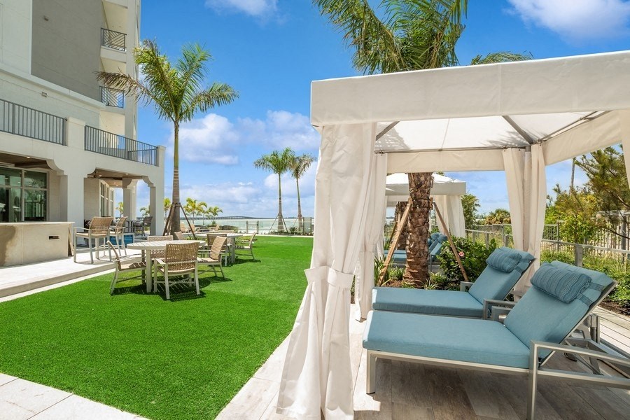 a patio with chairs and a table and palm trees