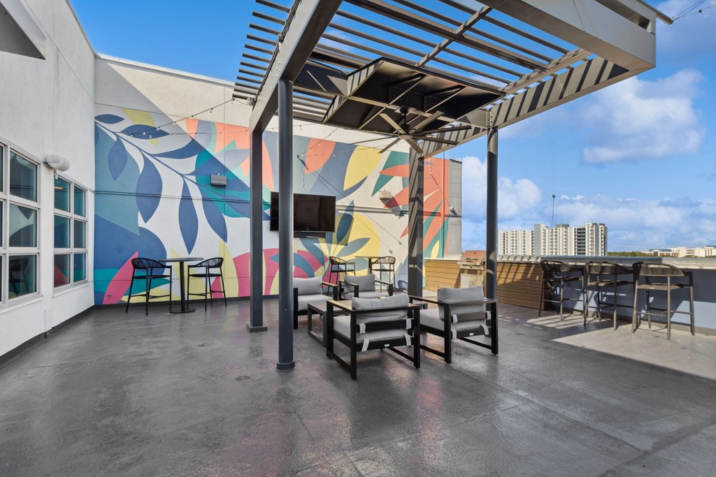 a patio with a mural on the wall and tables and chairs