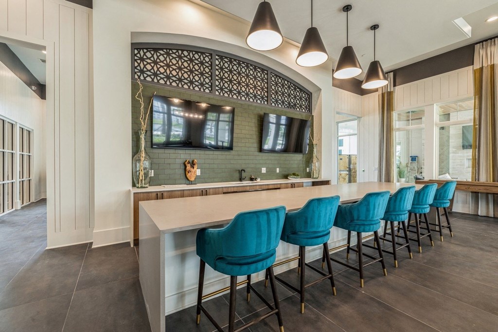 a long bar with blue chairs in front of a mirror