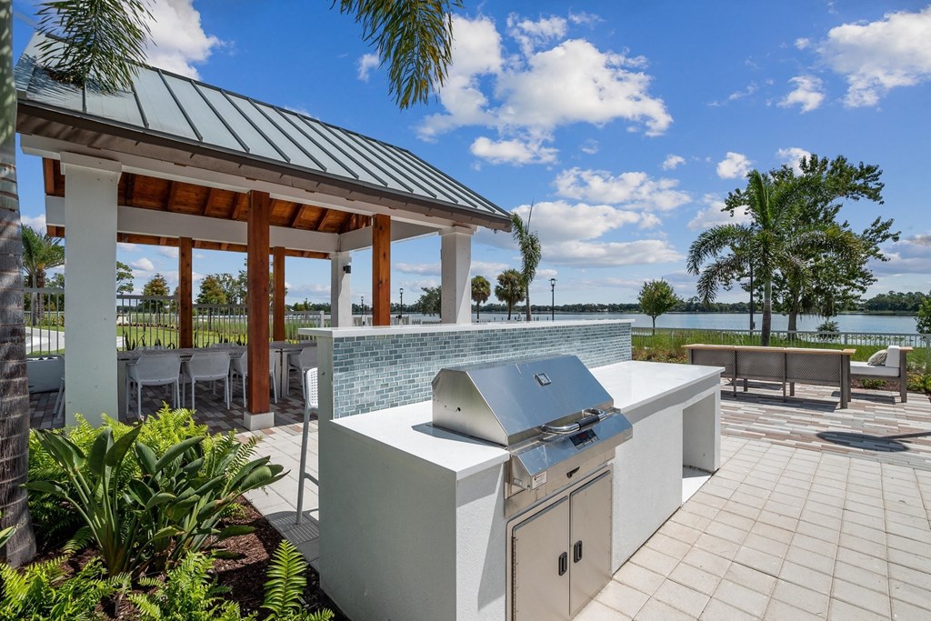 a patio with a grill and a pavilion with tables and chairs