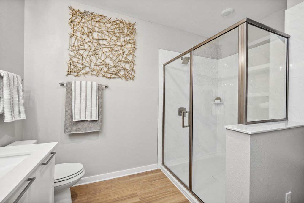 a white bathroom with a glass shower and a white toilet