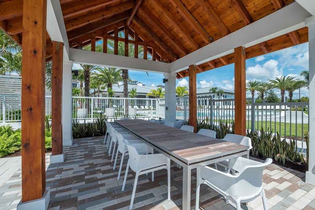 a covered patio with a wooden table and chairs