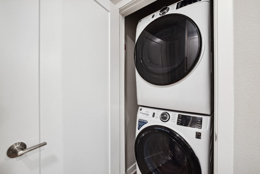 a white washer and dryer in a white closet next to a white door