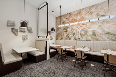 a dining room with tables and chairs and a large painting on the wall
