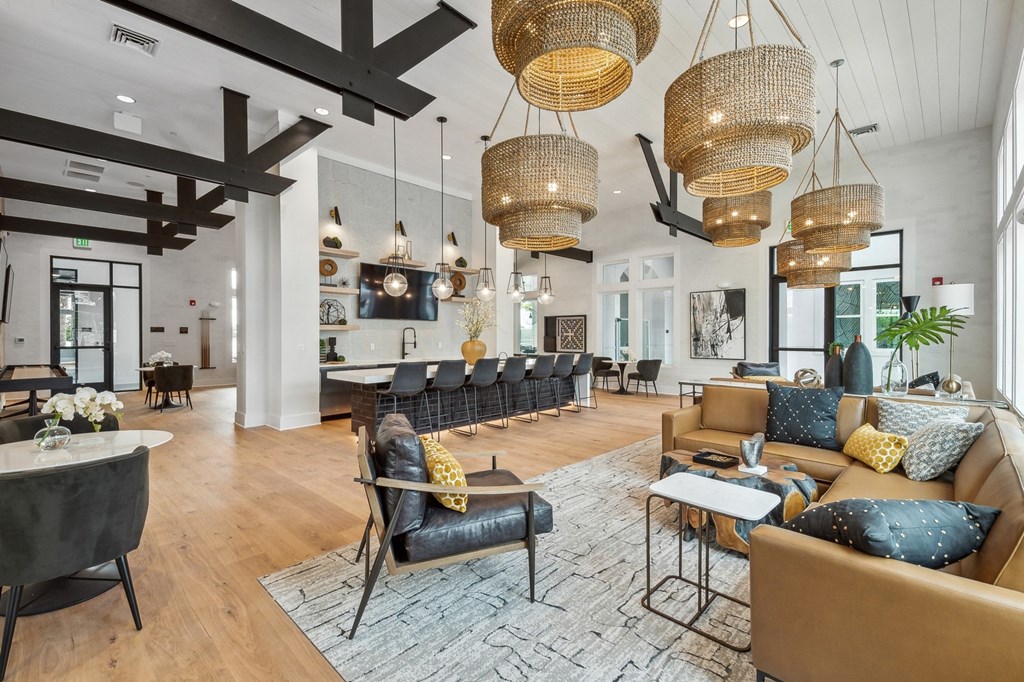 a large living room with couches and chairs and hanging lights