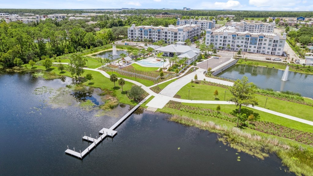 an aerial view of a park with a body of water and buildings