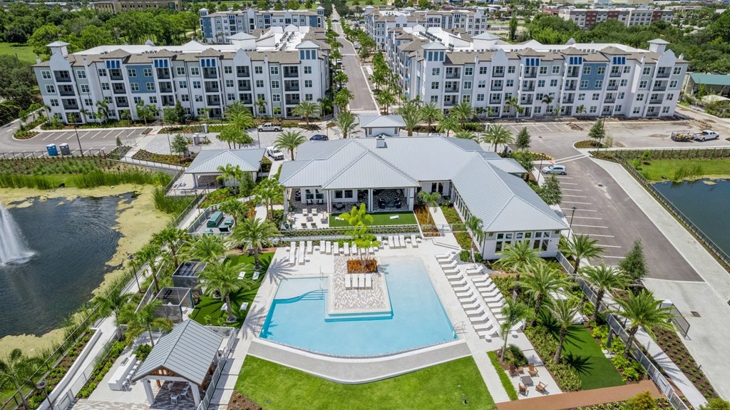 an aerial view of a resort with a swimming pool and a building with palm trees