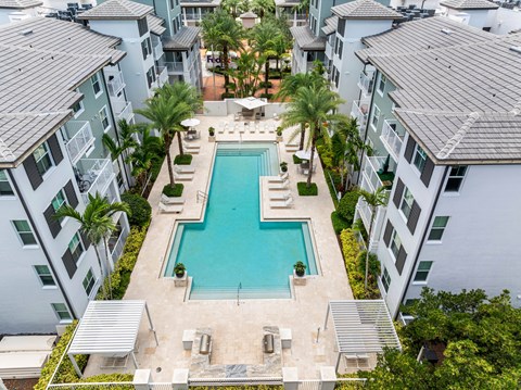 A swimming pool surrounded by buildings and palm trees.