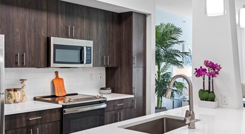 A modern kitchen with dark wood cabinets and a white countertop.