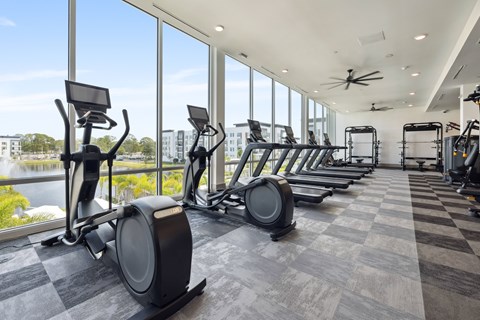 A gym with exercise equipment and a view of the outside.