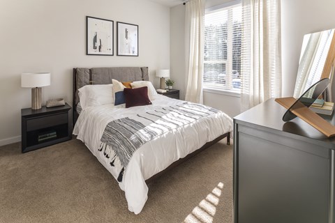 A bedroom with a large bed and a nightstand with a lamp.
