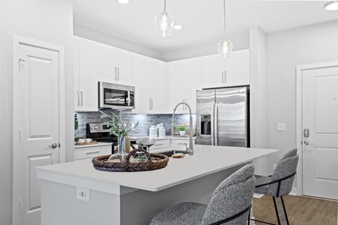 A kitchen with white cabinets and a white island with a basket on top.