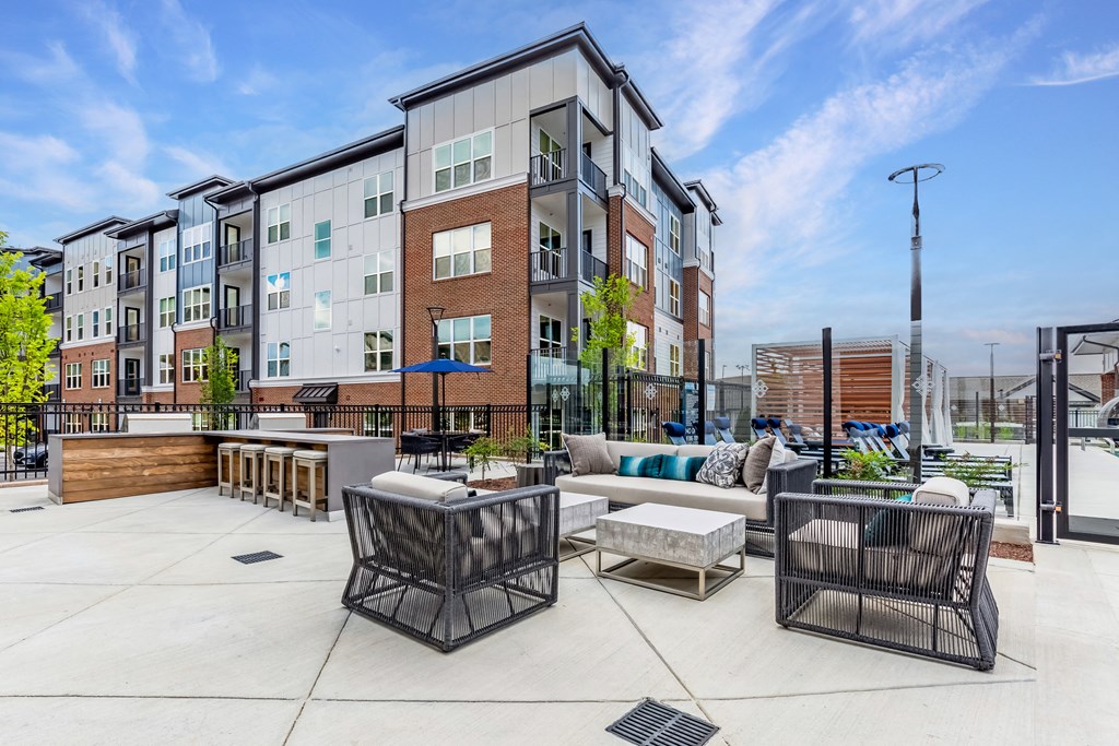an outdoor patio with furniture and an apartment building in the background