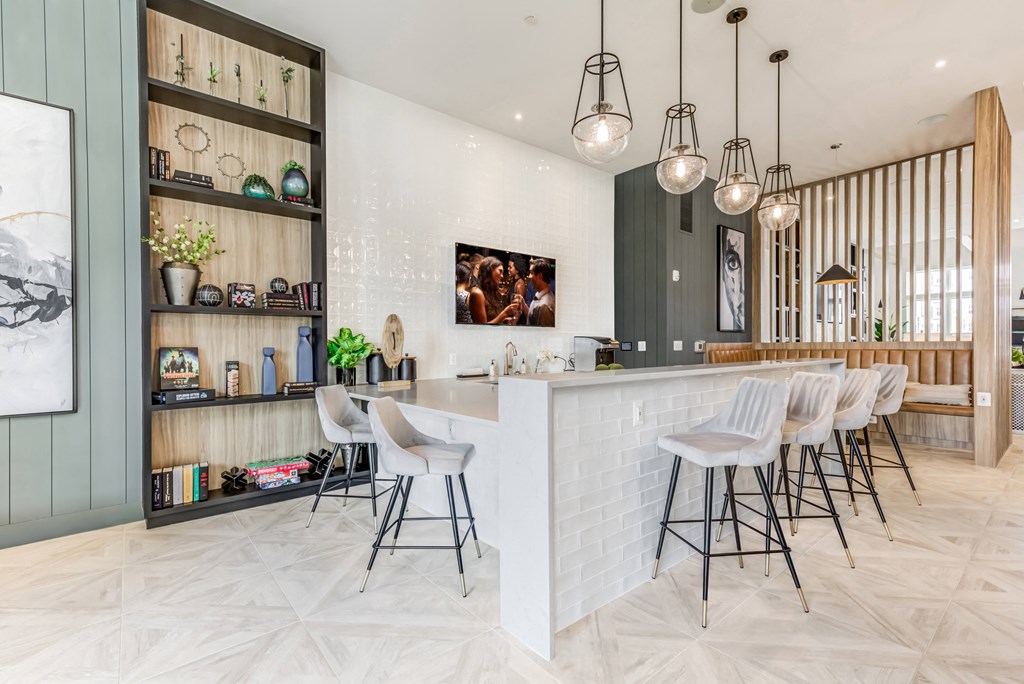 the kitchen has a large white counter with chairs and a bar with stools