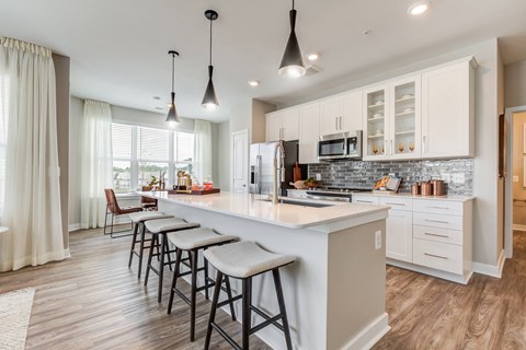 a kitchen with white cabinets and a large island with bar stools