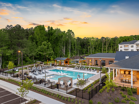 A large outdoor swimming pool surrounded by trees and a building.