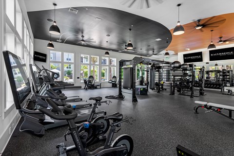 A gym with a variety of exercise equipment including treadmills, stationary bikes, and weight machines.