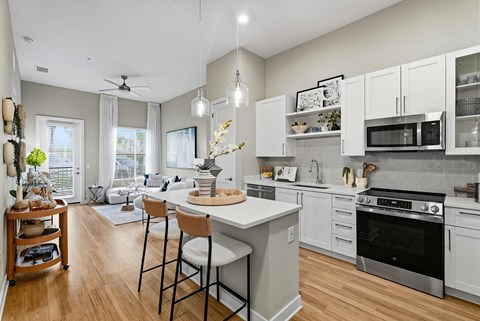 A kitchen with white cabinets and a wooden floor.