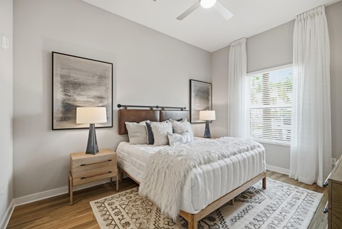 A bedroom with a large bed, a nightstand with a lamp, and a rug on the floor.
